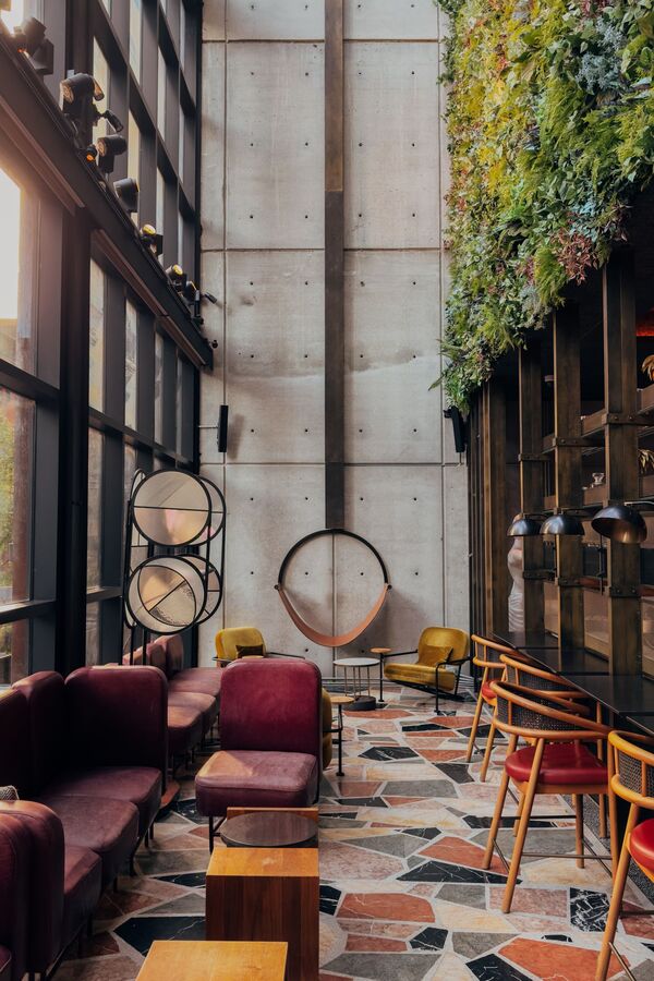 Lounge di un hotel con parete verde, cemento a vista e pavimento in marmo a palladiana